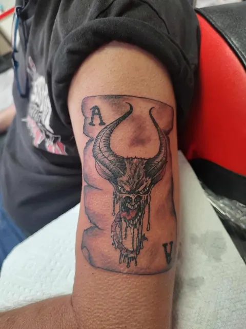 An ace card with a horned skull on the upper arm, black and gray