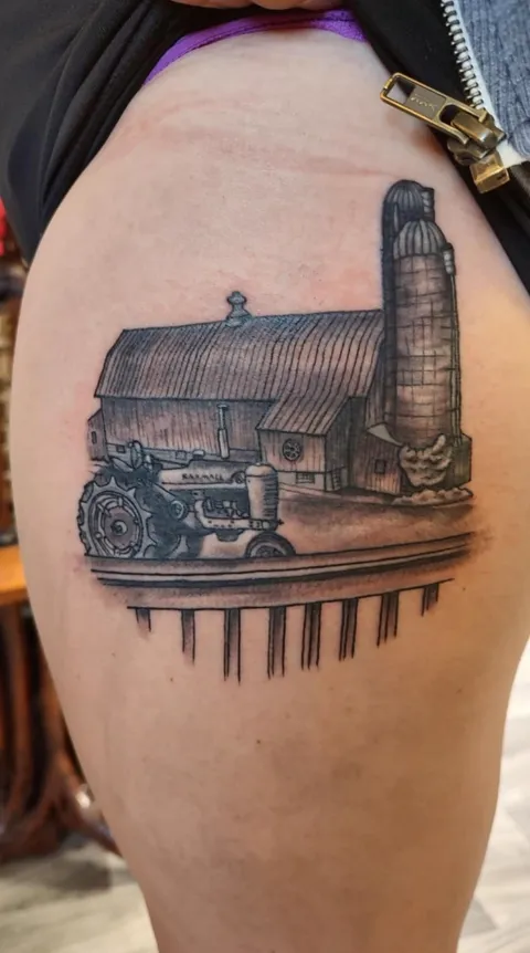 A barn, a silo and a tractor behind a fence on the thigh, black and gray