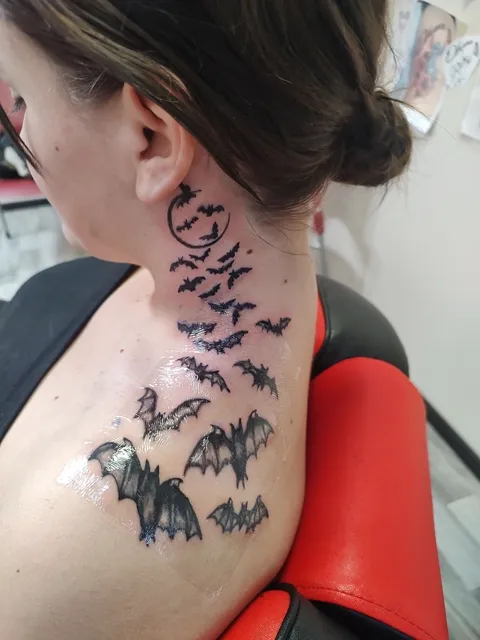 A flock of bats flying up the neck from the shoulder, black
