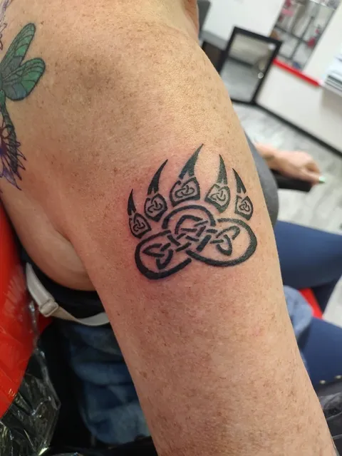 A bear paw with a Celtic knot on the upper arm, black
