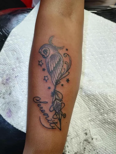 A small bird and stars above the word Serenity in script on the forearm