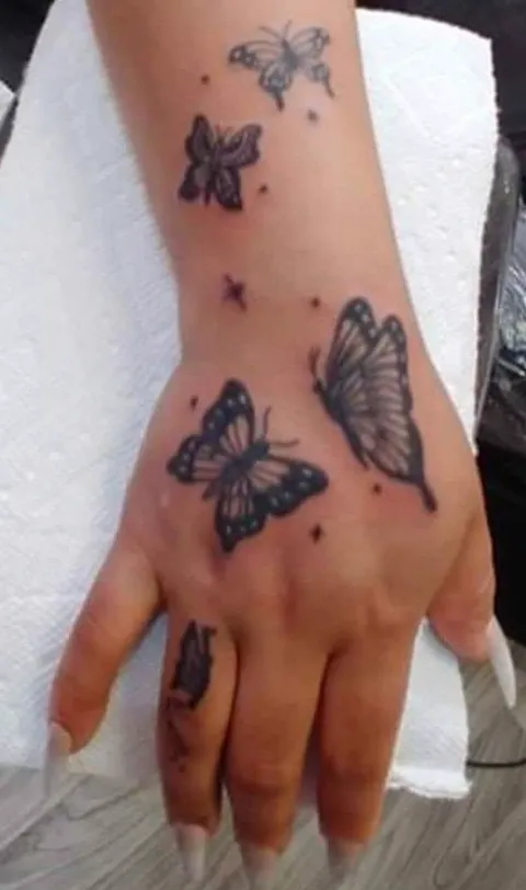 Butterflies across the back of the hand and a finger, black