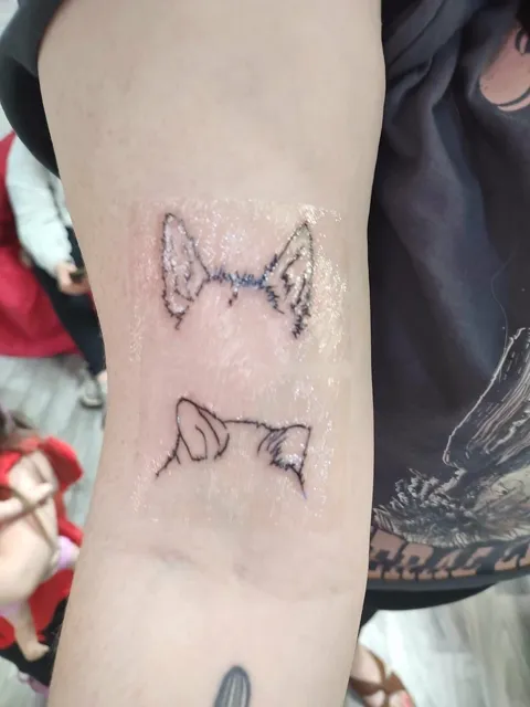 Two cat ear outlines on the forearm, fine line
