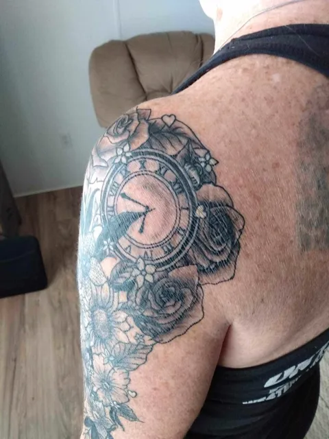 A clock among roses and flowers over the shoulder, black and gray