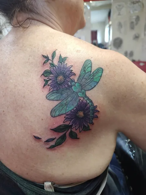 A dragonfly with purple flowers on the shoulder blade, in color