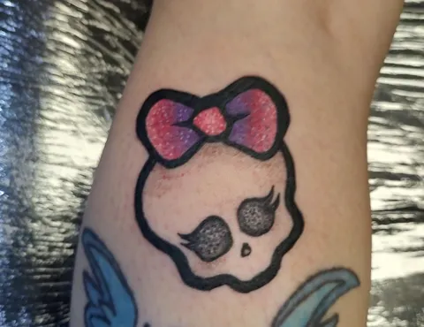 A cartoon skull with a pink glitter bow