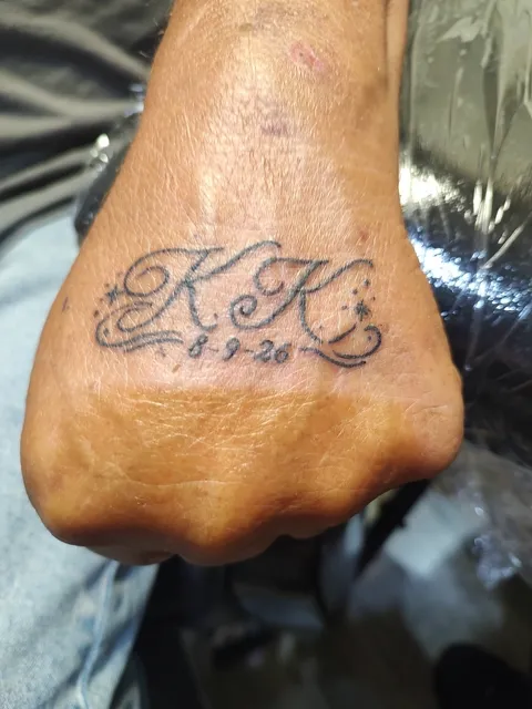 The initials KK in script with a date across the back of the hand