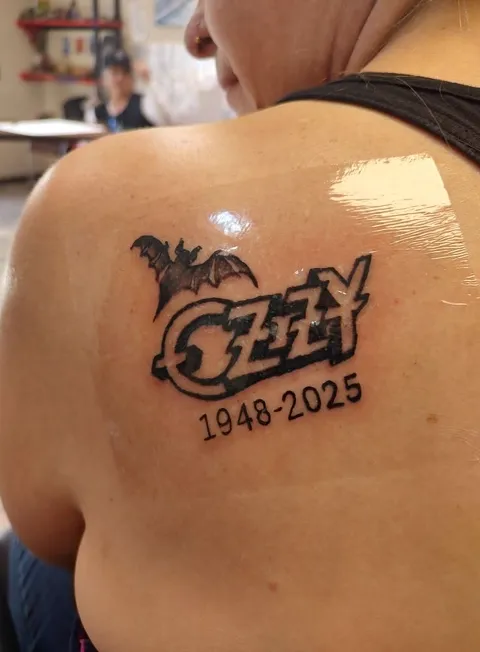 Ozzy in metal lettering with a bat and the years 1948 to 2025 on the shoulder