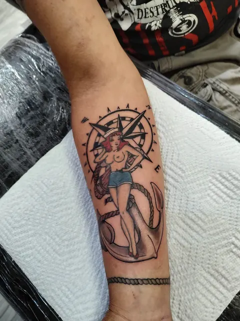 Pinup with a compass and an anchor on the forearm, in color