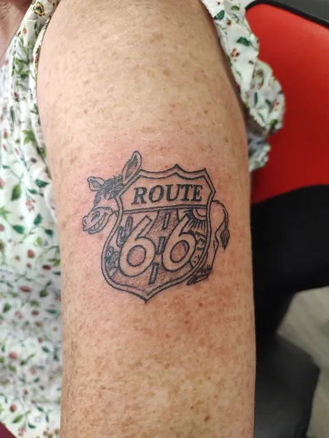 A Route 66 shield with a cow on the upper arm, black and gray