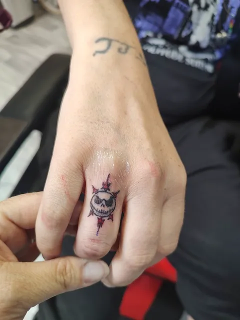 A small skull face inside a red diamond on a finger