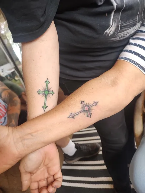 Two small crosses on two forearms, one filled in green